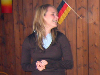 Chrissy lachend vor dekorierter Holzwand